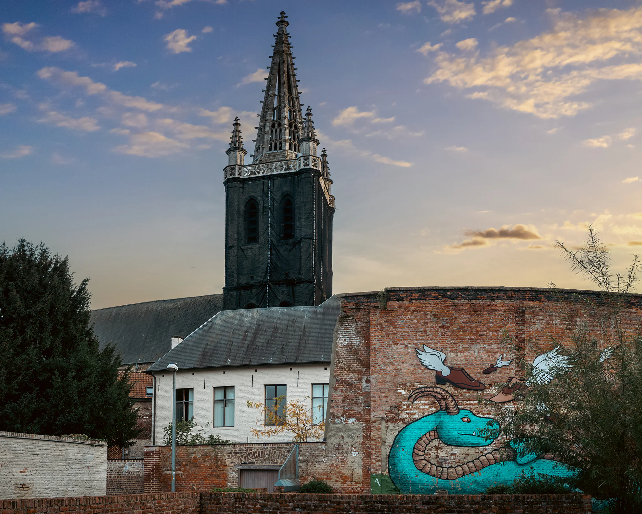 A large dragon mural seen beneath a church tower in Leuven.