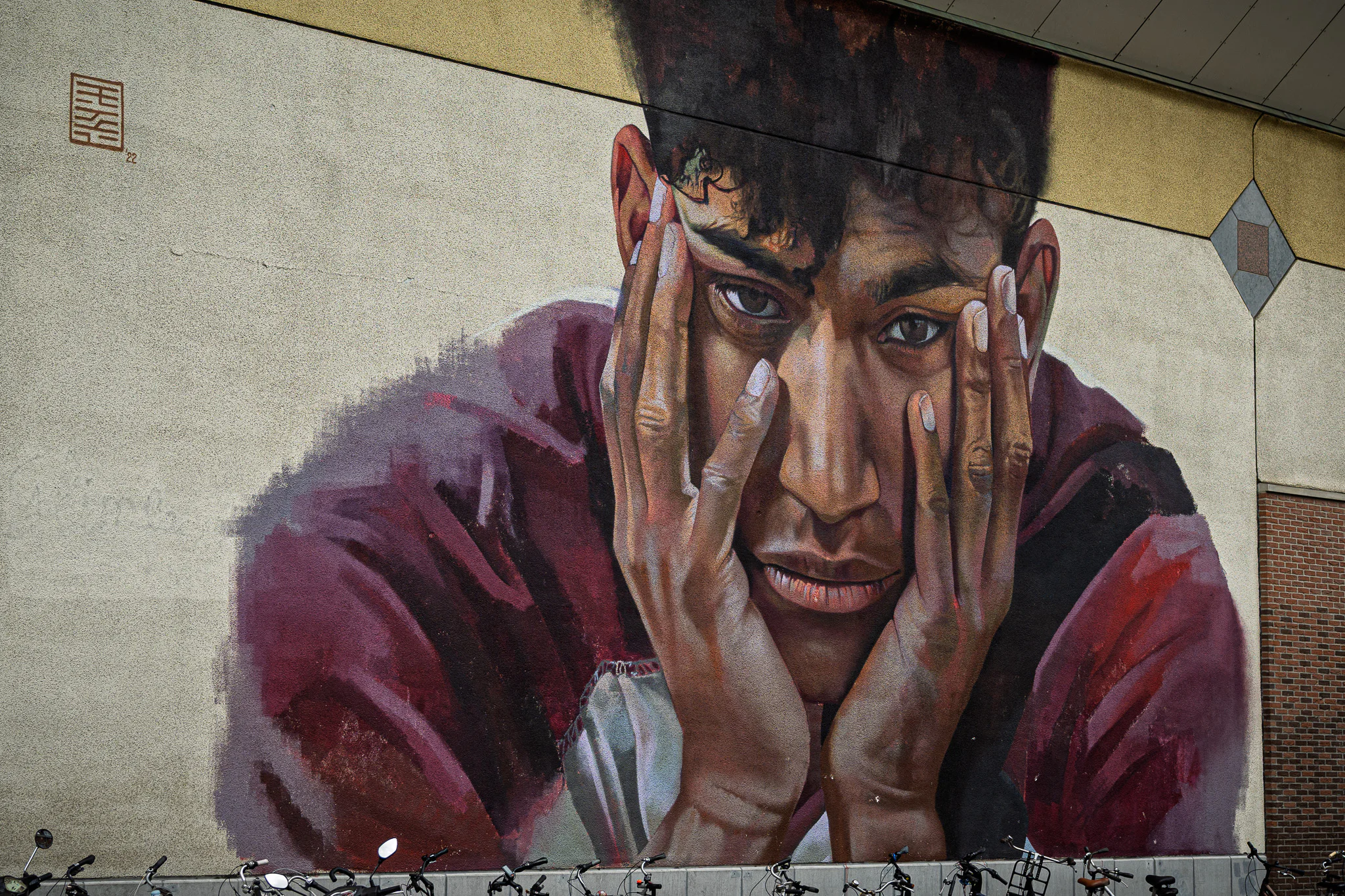 Case Maclaim's mural portrait of Sanda Dia looking outward from the wall of KU Leuven's Pieter De Somer auditorium.
